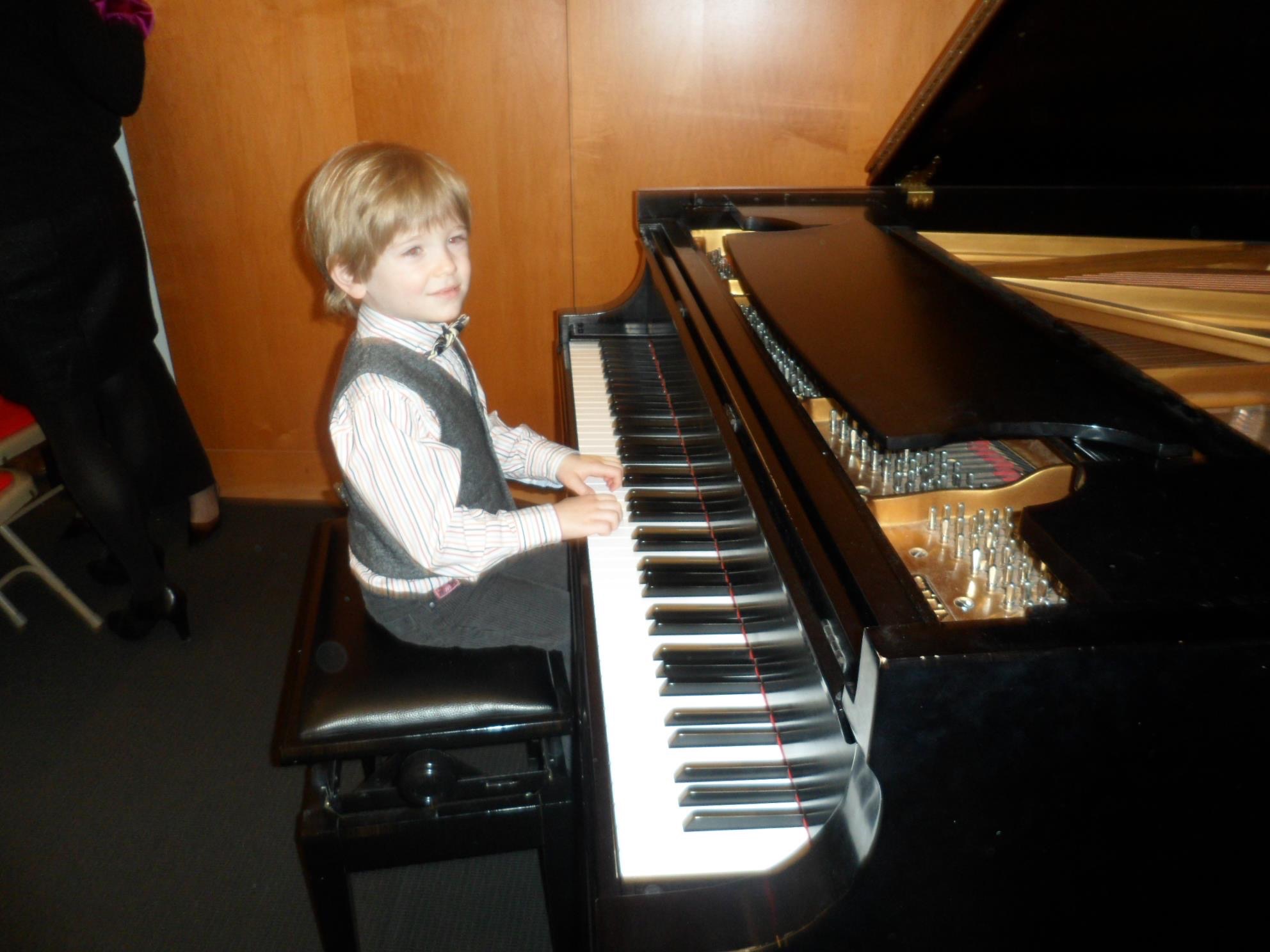 Lucas Voloshin as a young boy, playing a grand piano